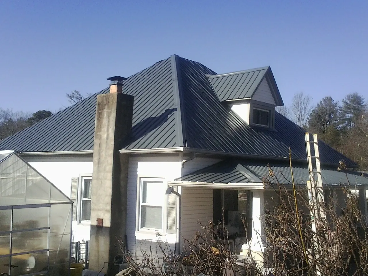 Dark blue standing seam metal roof on a white farmhouse with dormer — Slate & Tile Roof Repair by Roofing Brothers in Coeymans Hollow