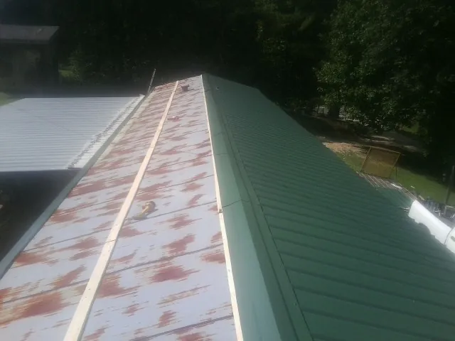 Old rusted panels beside newly installed green metal roofing — Wind Damage Roof Repair by Roofing Brothers in Coeymans Hollow
