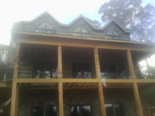 Dormers and porch framing on a large log home under construction — Roof Coating work by our crew in Coeymans Hollow