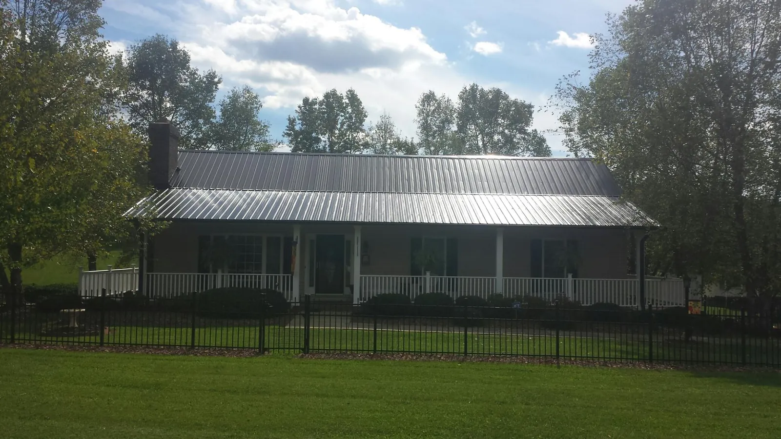 Gray metal roof on a brick ranch with a full width front porch — Gutter Guard Installation work by our crew in Coeymans Hollow
