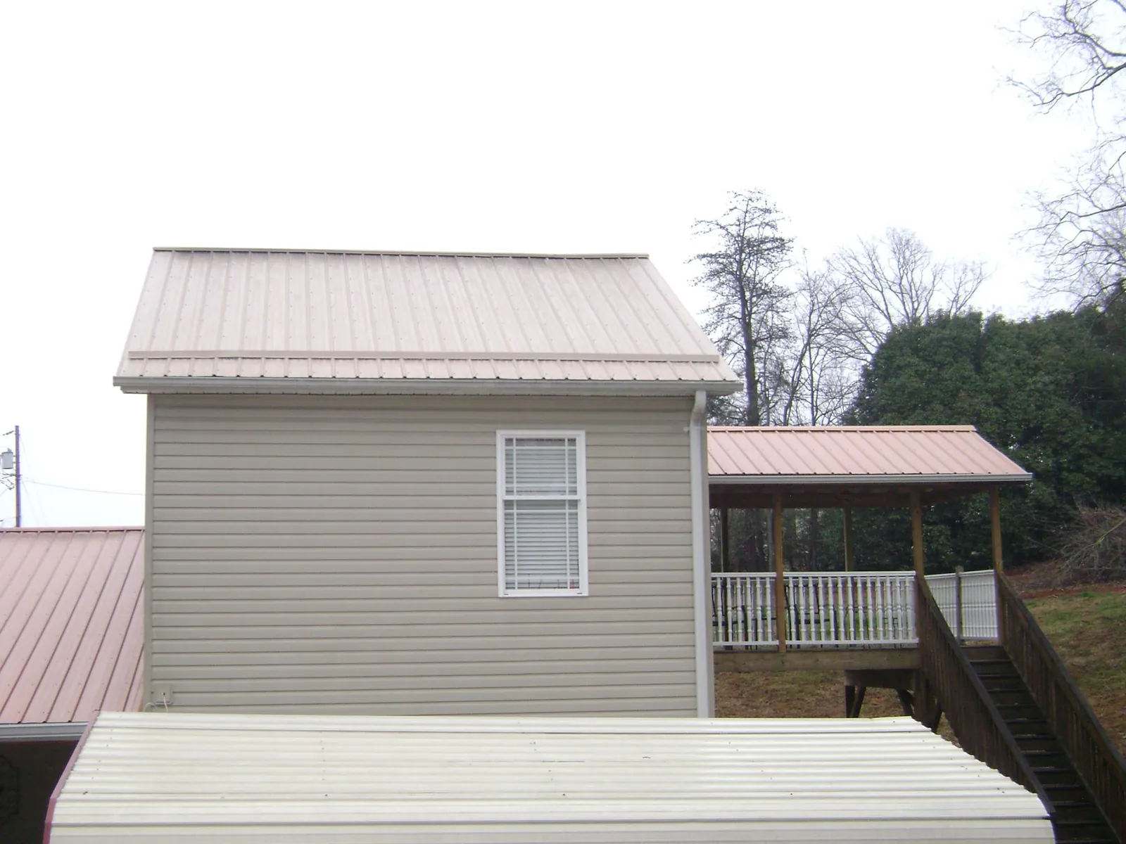Tan metal roofs on a two story addition and attached porch, from a Roof Replacement job in Coeymans Hollow