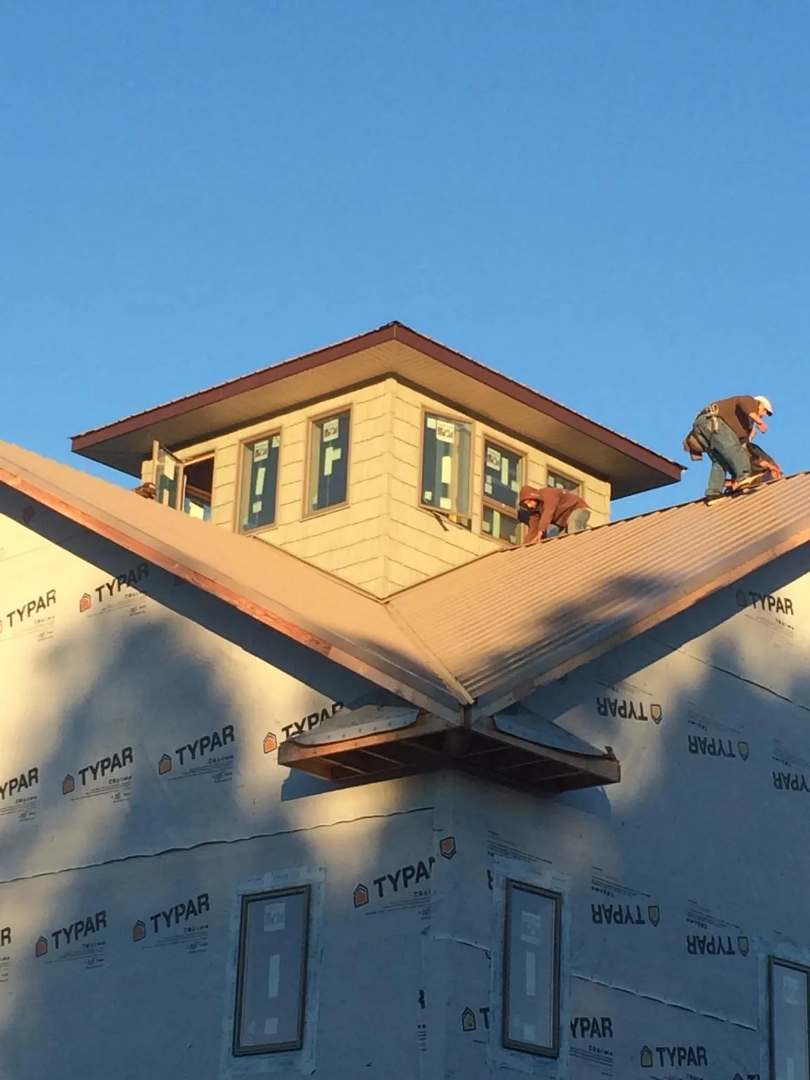 Roofers working around a rooftop cupola on a new metal roof at sunset — Roof Waterproofing in Coeymans Hollow by Roofing Brothers